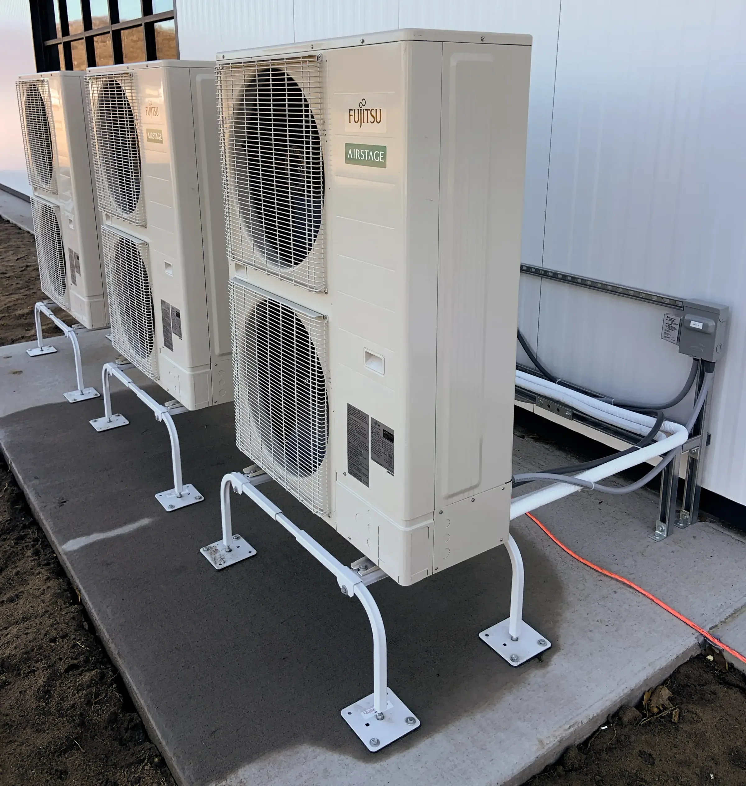 Commercial Fujitsu outdoor air conditioning units installed beside a building