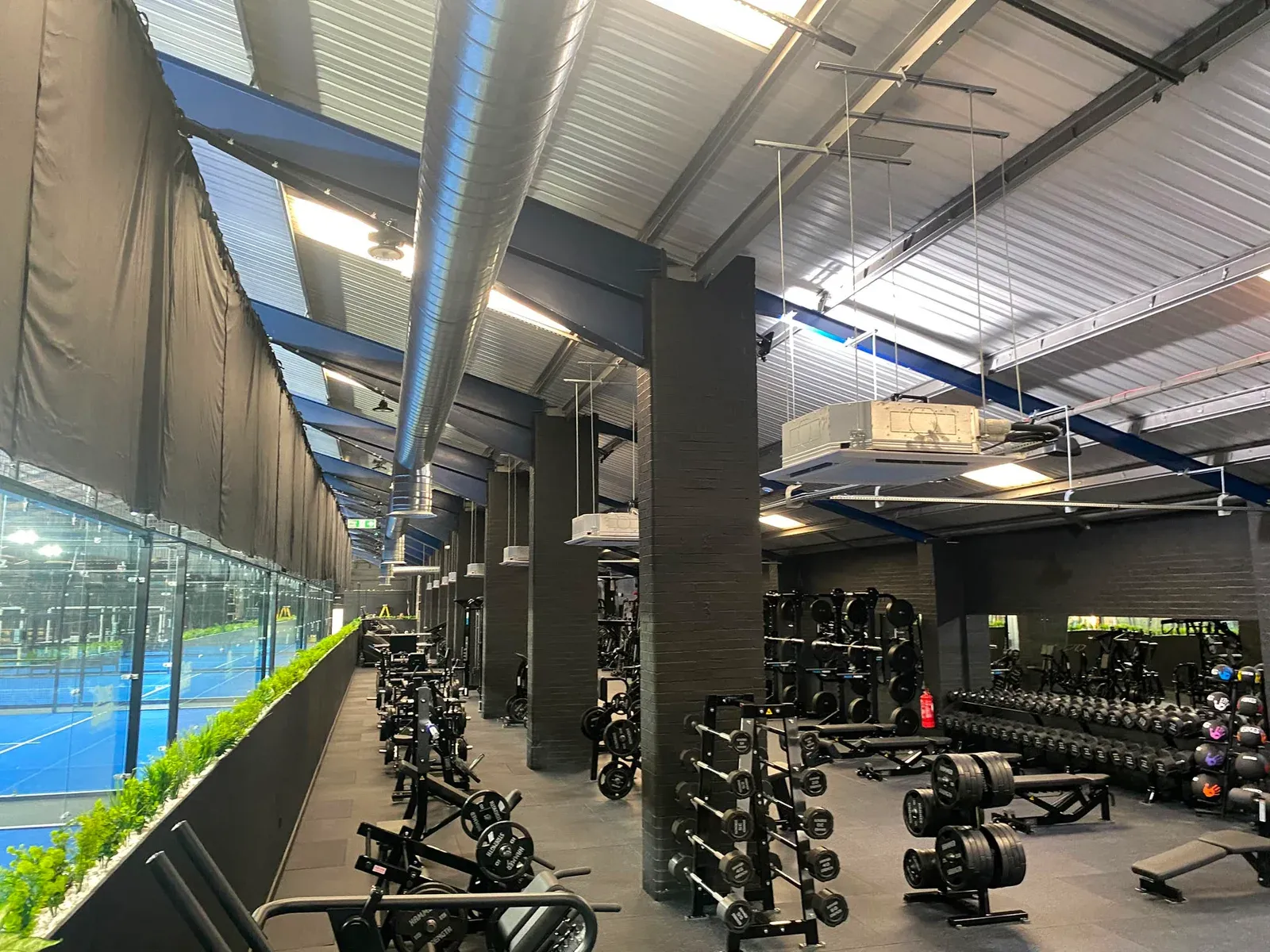 Ceiling-mounted air conditioning units and exposed ductwork installed in a gym