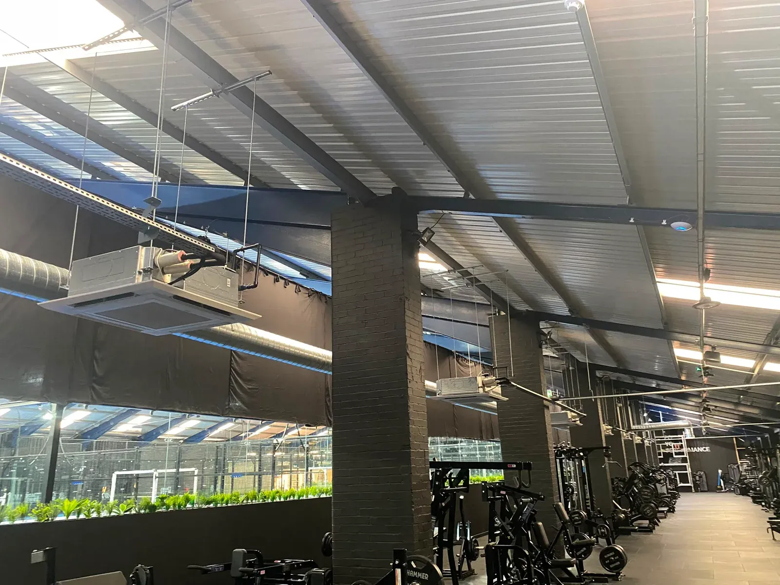 Ceiling-mounted air conditioning cassettes above a gym weights area