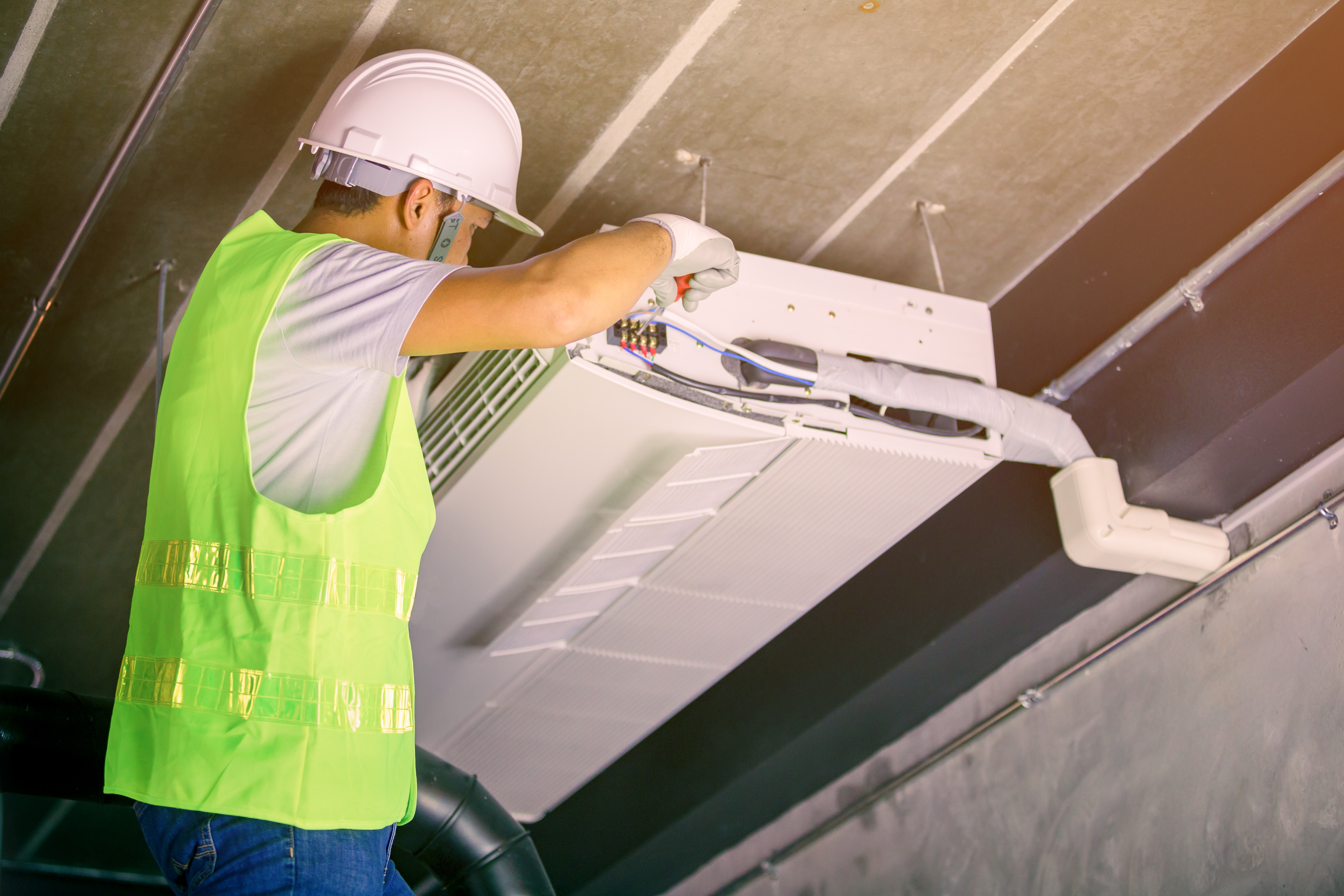 Professional HVAC technician in uniform installing a modern air conditioning unit